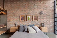 Modern industrial bedroom with exposed brickwork wall 
