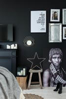 Black painted wall with artwork in modern bedroom 