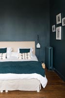 Teal painted walls and matching bedspread in modern bedroom 