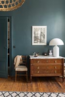 Classic wooden chest of drawers in modern bedroom with teal painted walls 