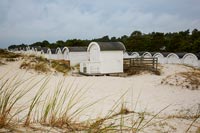 Tiny white wooden cabins along coastal shoreline 