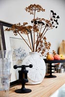 Dried flowers and seed heads in vase on shelf 