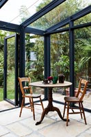 Round table and two wooden chairs in modern conservatory 