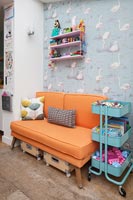 Flamingo wallpaper and orange sofa in colourful childrens room 