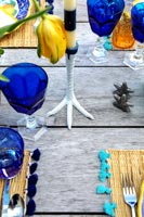 Outdoor wooden table laid for lunch with chicken foot candle holder 