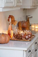 Golden decorations, pumpkins, champagne and glasses on kitchen worktop 