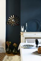 Classic dining room with painted dark blue walls and white furnishings 
