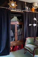 Black wall curtains open to reveal wooden cabinet 