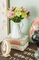 Vintage jug of flowers on pile of books 