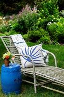 Wooden deck chair with cushion and blue glazed side table 