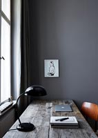 Wooden desk and chair in corner of modern grey painted study 