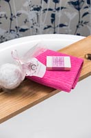 Pink towel on wooden bathroom shelf with toiletries 