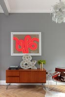 Vintage sideboard and colourful artwork in modern living room 