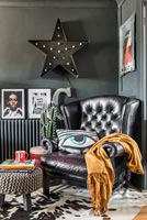 Black leather Chesterfield style armchair in corner of modern living room 