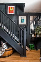 Pet dog in barrel bed under black painted staircase 