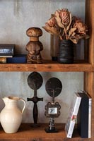 Wooden bookshelves with African ornaments and dried flowers 