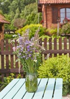 Wildflowers arranged in glass jar on table in country garden