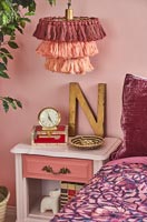 Tassel lampshade over pink bedside table 