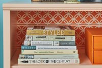Stack of books on bookcase with patterned backing paper 