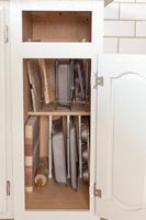 Kitchen cupboard full of baking trays and utensils 