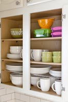 Kitchen cupboard full of crockery and storage boxes 