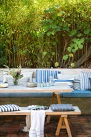 Wooden outdoor dining table and built-in bench seat covered in cushions 