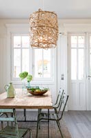 Wicker lampshade over dining table with vintage chairs 