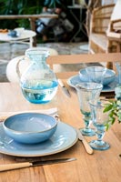 Detail of blue crockery and glassware on outdoor dining table 