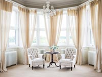 Armchairs in curved window of classic bedroom  