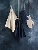 Oven gloves and tea towels against painted black wall 