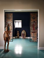 Stained glass screens and carved wooden figure in bedroom doorway 