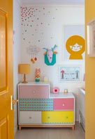 Colourful chest of drawers and artwork in childrens room 