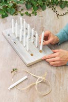 woman placing candles into drilled holes in wood