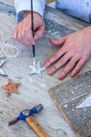 Woman painting wooden stars with white paint