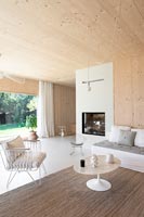Modern timber clad living room with view to garden through open bi-fold doors 