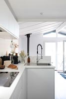 Modern kitchen with view to small open plan living space and patio doors 