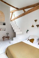 Staircase in modern white and brown bedroom with exposed beams 
