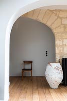 Large painted empty urn in hallway with exposed stone wall 