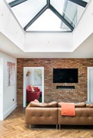 Exposed brick wall with wall mounted television and leather sofa 