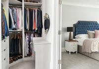 View of clothing hanging in large bedroom wardrobes 