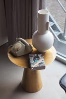 Large modern vase and vintage telephone on small wooden side table 