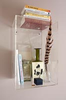 Clear perspex wall mounted shelf with books and glassware 