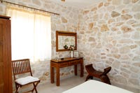 Exposed stone walls and wooden furniture in country bedroom 