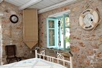 Country bedroom with exposed stone wall and maritime themed mirror 