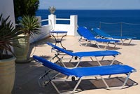 Blue recliners on terrace overlooking sea  