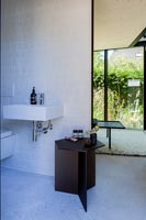 Black side table in modern bathroom with view to bedroom window