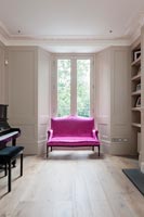 Bright pink two-seater sofa in classic living room 