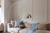 Large silver floor lamp in living room with painted wooden panelled walls 