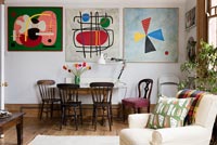 Dining area and wall of colourful modern artwork in open plan living space. 
Cushion by Nichollette Yardley-Moore www.vintagecushions.com