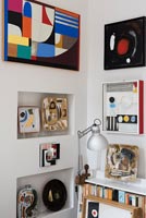 Colourful display of artwork in corner of eclectic living room 